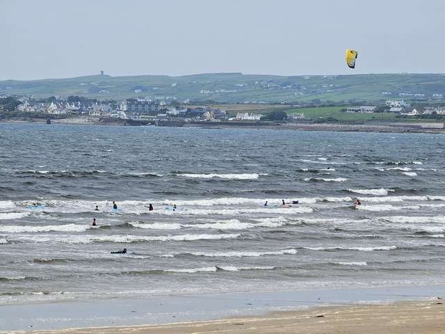 Kite surfer in the middle of the beach with a few beginner surfers in the shallows